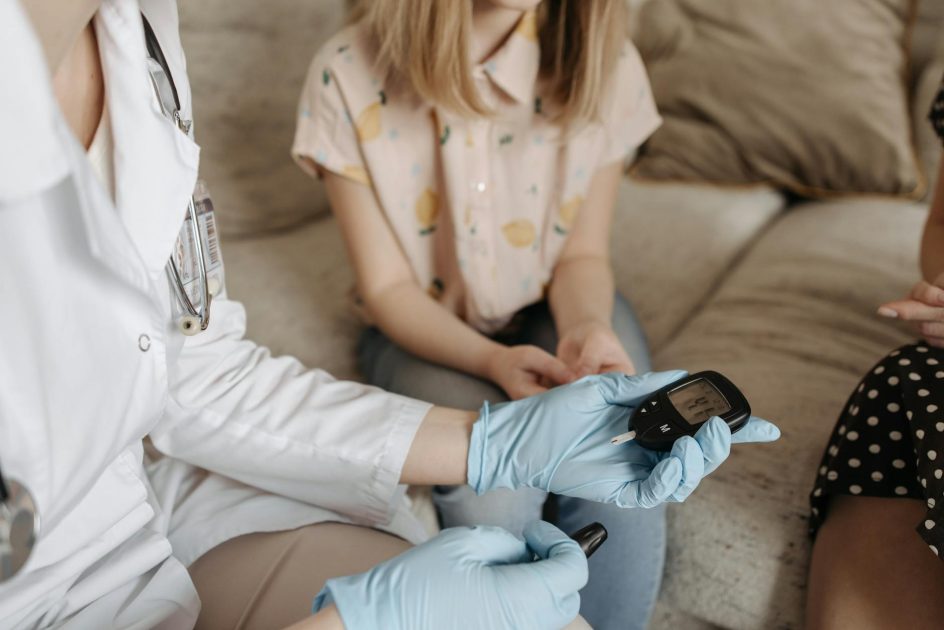 Alat Cek Gula Darah Akurat: 7 Rekomendasi Terbaik 2025 1 Doctor using a glucose meter to check a patient's blood sugar during a medical consultation.