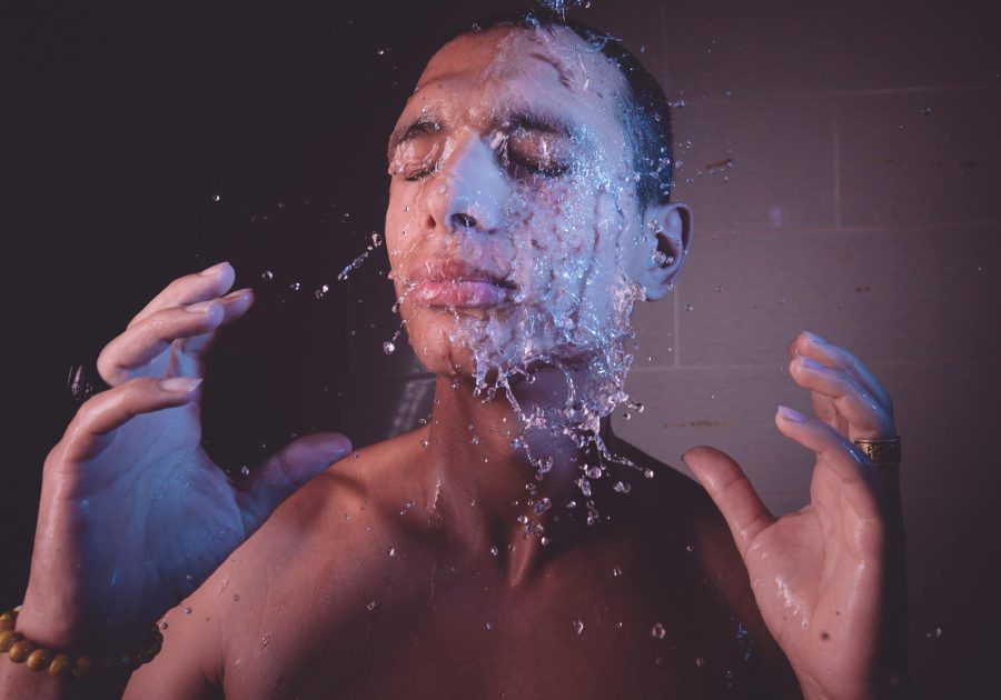 Man with eyes closed enjoying a refreshing splash of water on face.