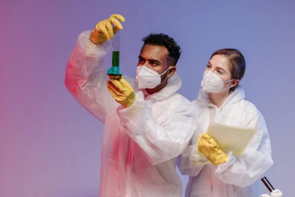Two scientists in personal protective equipment conducting an experiment in a laboratory setting.