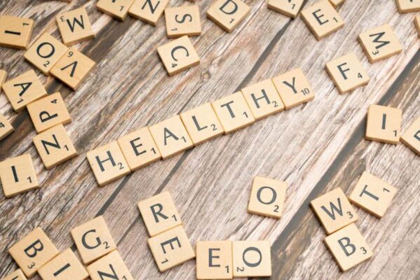 Wooden letter tiles arranged on a wooden surface spelling out 'healthy', symbolizing wellness.