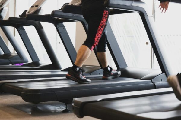 A person walking on a treadmill in a modern gym setting, focusing on fitness.