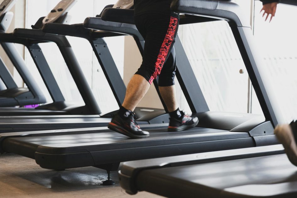 A person walking on a treadmill in a modern gym setting, focusing on fitness.