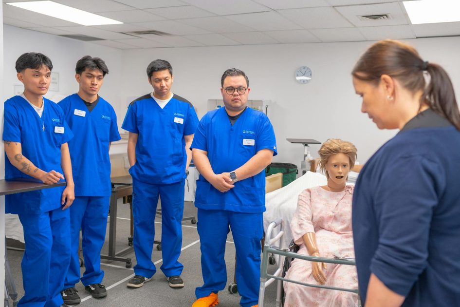 Adaptor CO2 Victoria S2200 - Sahil Singh Nursing students in blue scrubs practicing patient care using a medical mannequin.