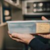 Close-up of hands holding a urine specimen container in a lab environment.