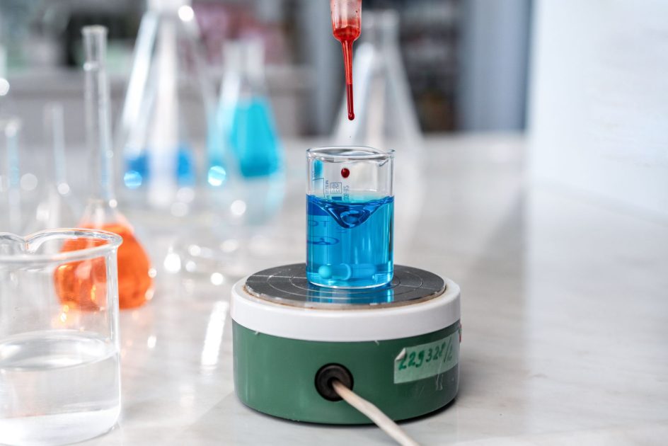 Corning Platform Flask Clamps 125 mL - Ivan S A laboratory experiment with a dropper adding red liquid to blue solution in glassware on a magnetic stirrer.