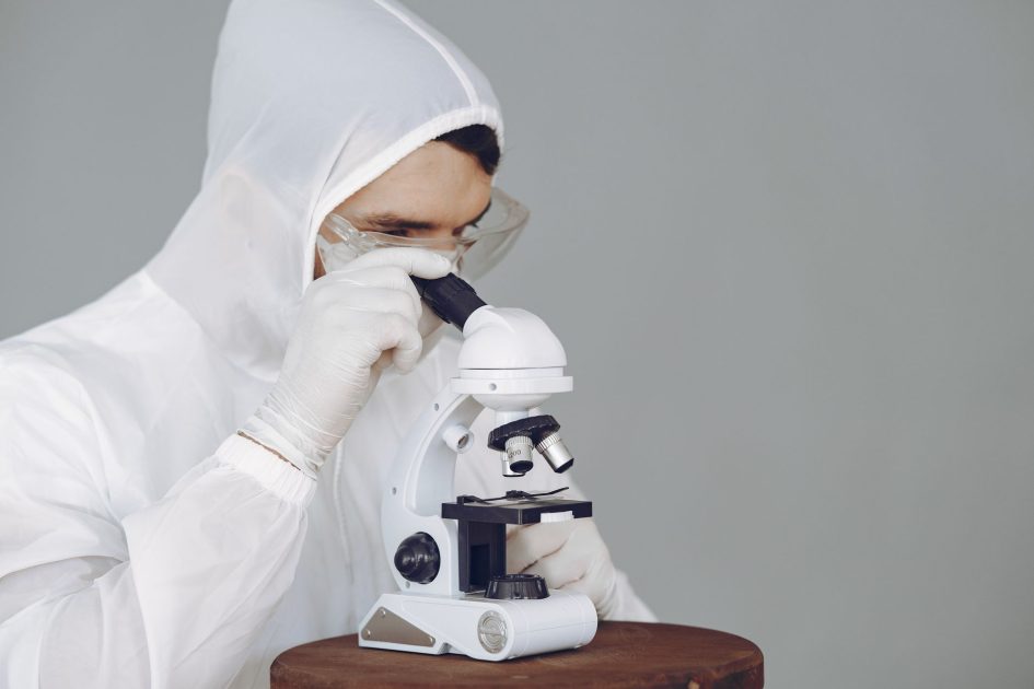 Karl Fischer Coulometer - Gustavo Fring Scientist in protective gear using a microscope, focused on research and analysis.