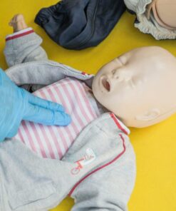 A person demonstrates infant CPR on a manikin, highlighting first aid techniques.