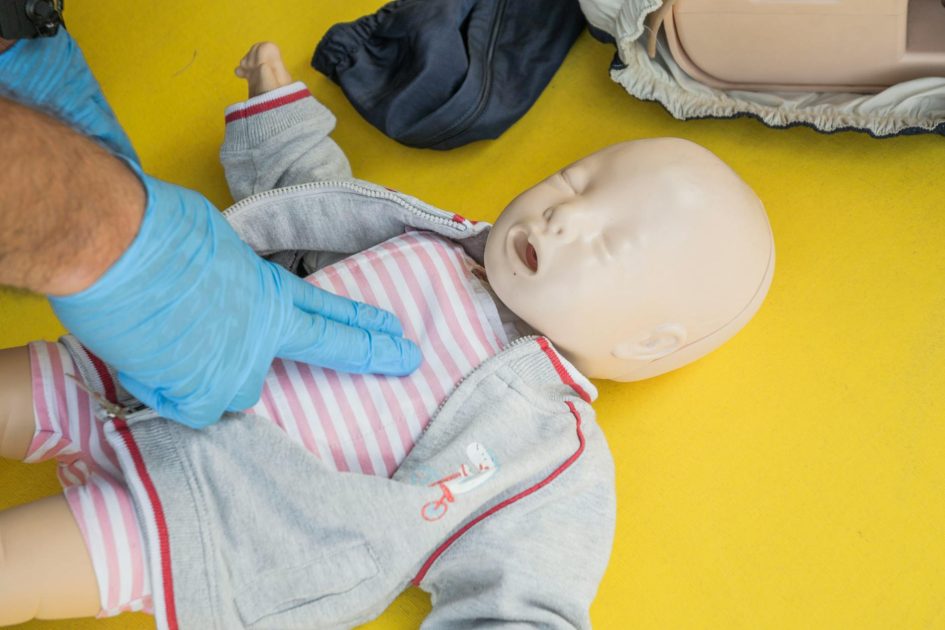Laerdal Mini Anne Plus manekin CPR - SHOX ART A person demonstrates infant CPR on a manikin, highlighting first aid techniques.