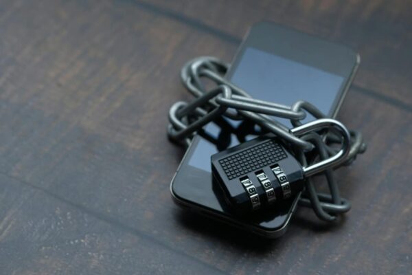 Close-up of a smartphone wrapped in a chain with a padlock, symbolizing strong security.