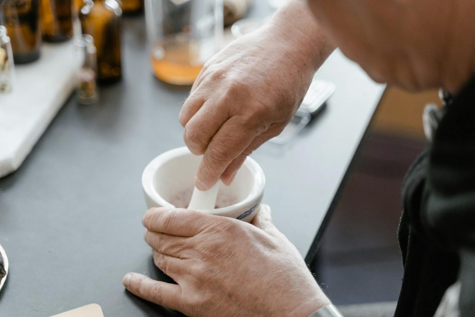 PTFE Adapter for Cooling Grinding: Solusi Lab Terbaik 2024 1 Hands using a mortar and pestle in a lab setting with glass bottles in the background.