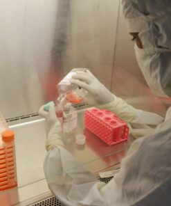 Scientist in protective clothing pouring liquid in a laboratory environment.