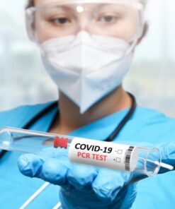 A healthcare worker holding a COVID-19 PCR test tube, showcasing medical safety measures.