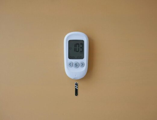 Close-up of a digital glucose meter displaying blood sugar level on a brown surface.