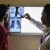 Karixa X-Ray Film Viewer KA 27-02A | Alat Baca Rontgen TKDN 1 A doctor reviews X-ray images with a patient in a medical facility, highlighting healthcare interaction.