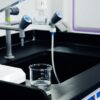 Close-up of laboratory equipment used for water filtration, featuring beakers and faucets.