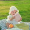 LAERDAL Alat Pengisap Lendir Bayi Penguin | Original 1 Adorable baby playing with a pink tablet on a picnic blanket outdoors.