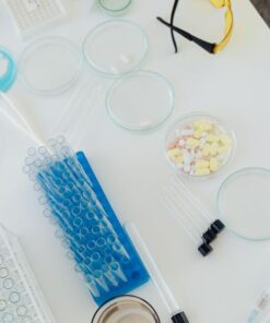 Aerial view of laboratory equipment including petri dishes, pills, test tubes, and syringes.