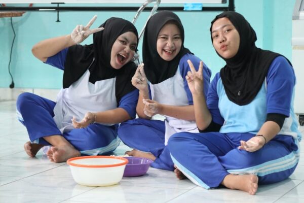 Three smiling women in hijabs making peace signs.