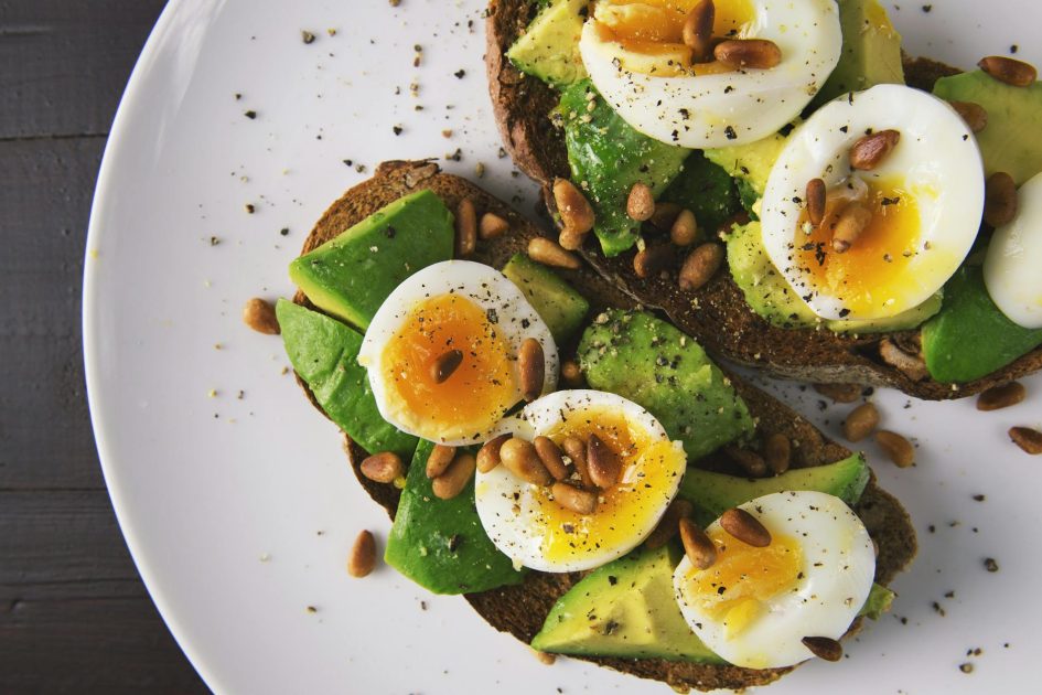 Benarkah Telur Omega 3 Tak Boleh Didadar? 5 Fakta Ilmiah 1 Delicious avocado toast topped with soft-boiled eggs and pine nuts on a white plate.