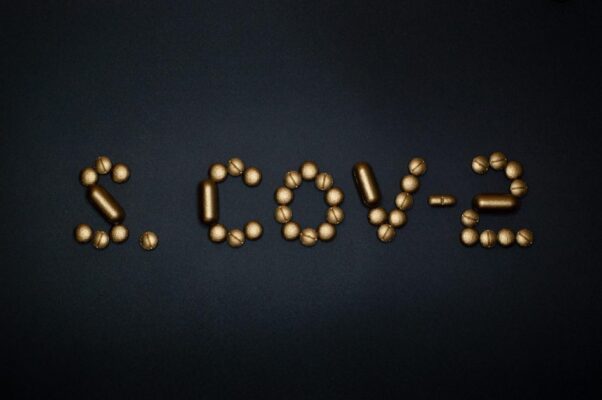 Golden pills arranged to spell 'S. COV-2' on a dark background, symbolizing medical concepts.