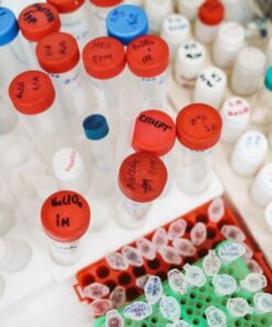 Lab test tubes and bottles with colorful caps and labels seen from above in a scientific setting.