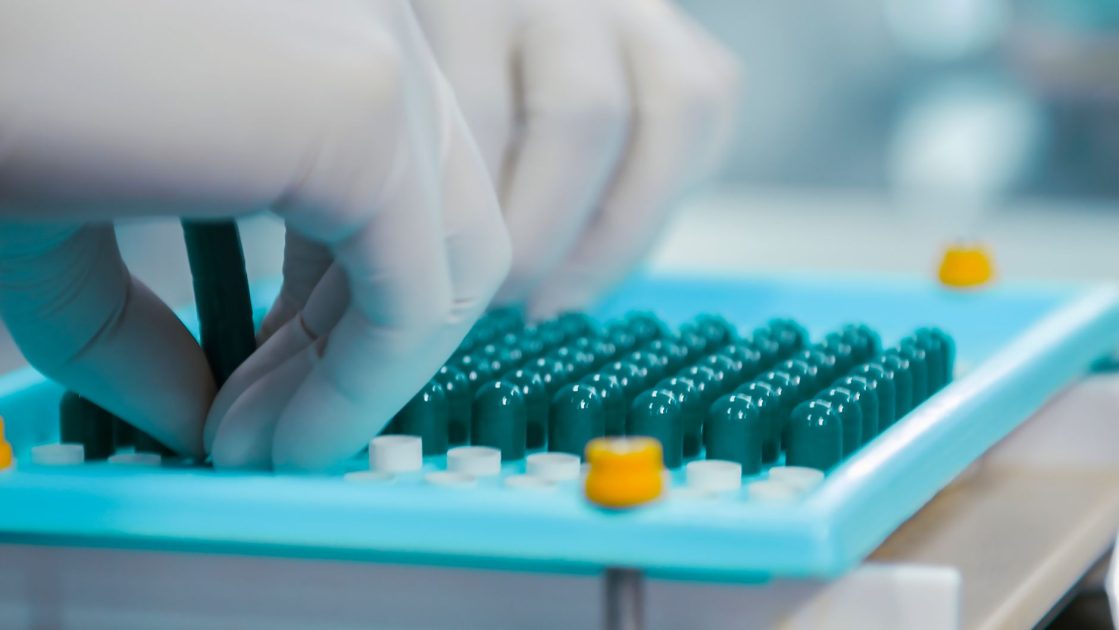 Capsule Seam Analyzer: Panduan QC Kapsul Farmasi 2026 1 Close-up of gloved hands working with capsules in a pharmaceutical lab setting.