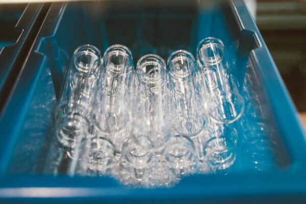 A collection of empty glass test tubes stored in a blue laboratory tray under bright lighting.