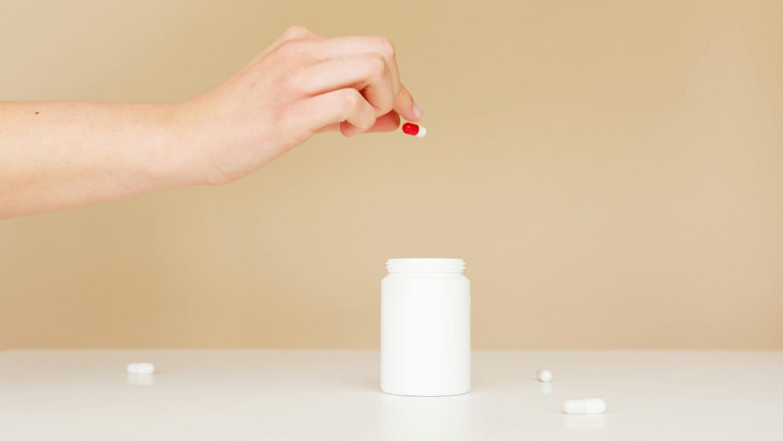 7 Cara Penggunaan Gliserol yang Benar & Efek Sampingnya 1 Side view of crop faceless female putting painkillers scattered over table back in white plastic jar