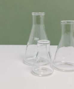 A set of three clear glass laboratory flasks on a clean white and green background, ideal for science themes.