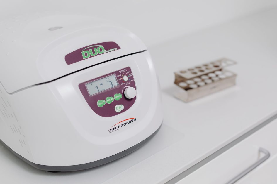 Close-up of a modern laboratory centrifuge on a sterile white surface, used in medical testing.