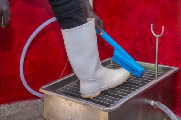 Person scrubbing boots with brush in a stainless steel wash basin in Eldoret, Kenya