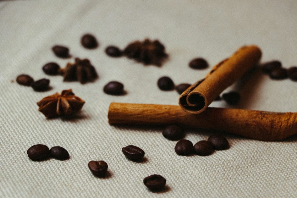 Cuma Tambah Bumbu Dapur Kopi: 7 Manfaat Ajaib untuk Kesehatan 1 Close-up shot of cinnamon sticks, coffee beans, and star anise on a textured surface.
