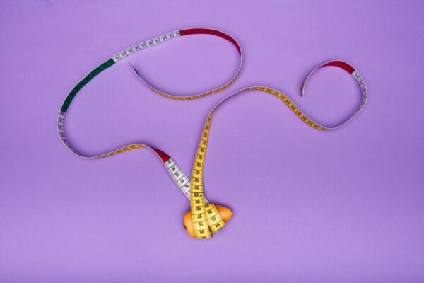 A measuring tape artistically wraps around an orange on a vivid purple background. Perfect for creative concepts.
