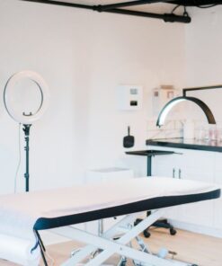 Bright and modern medical spa room featuring massage bed and studio lighting.