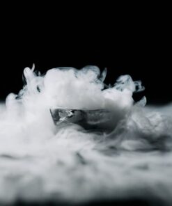 Abstract image of smoke wafting over an ice cube against a black background, creating a mysterious atmosphere.