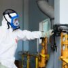 Industrial worker in protective gear inspecting machinery for safety compliance in Indonesia.