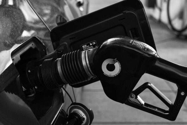Detailed close-up of a refueling nozzle in monochrome at a gas station, highlighting the petrol filling process.