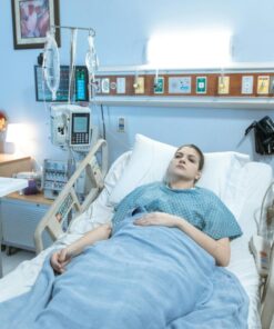 A young woman lies in a hospital bed during her recovery process in a calm, well-equipped room.