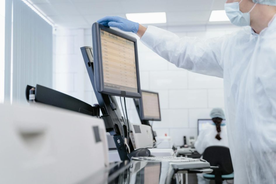 Kalibrasi Clean Screen: 7 Langkah Perawatan Optimal 1 Researcher in PPE reviews data on a digital screen in a modern laboratory setting.