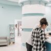 Jual Kiosk Digital 86 Inch Non-Touch 4K UHD | Arjuna 1 Healthcare professionals assisting at a modern clinic reception desk.