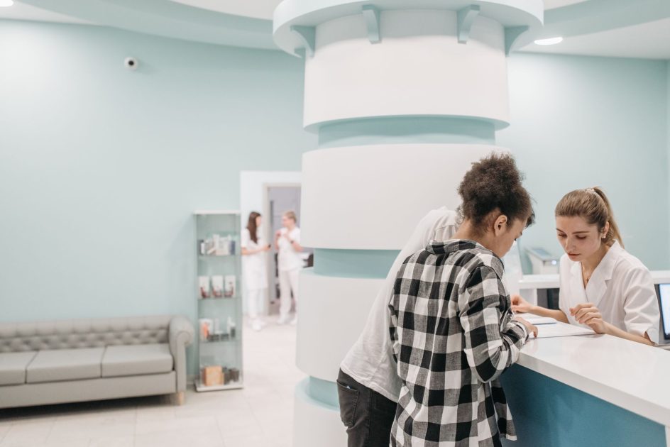 kiosk digital 86 inch non-touch - Pavel Danilyuk Healthcare professionals assisting at a modern clinic reception desk.