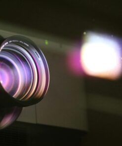 Close-up view of a projector lens with light reflections, highlighting optics and technology.