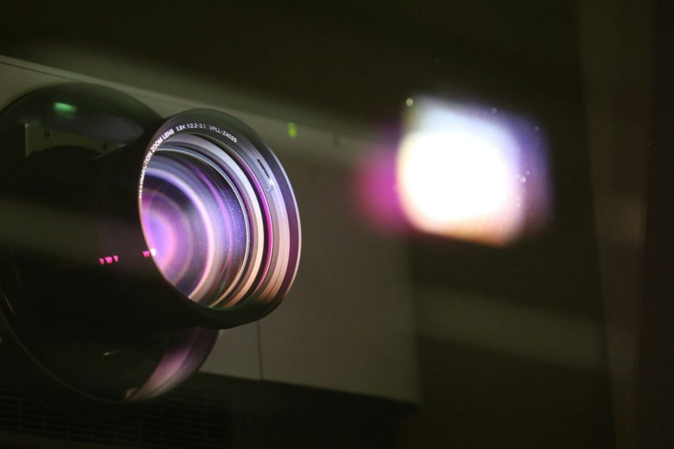 lensa zoom fokus pendek proyektor Sony VPLL-Z7008 - Ann H Close-up view of a projector lens with light reflections, highlighting optics and technology.