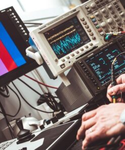 Technician operating laboratory electronic testing and measurement devices with colorful display.