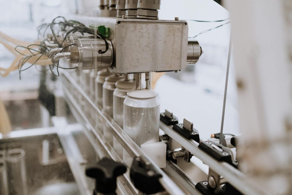 mesin kemasan karton otomatis untuk botol - cottonbro studio Close-up of an automated can filling machine in a beverage production line.