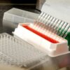Close-up of an automated pipetting system dispensing liquids in a scientific laboratory.
