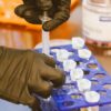 Close-up of gloved hands using syringe for precise work in a lab setting.
