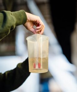 A person holding a measuring cup with liquid, focusing on precision in a laboratory environment.