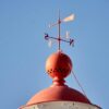 Penunjuk Arah Angin RY-FX-01 - Akurat & Tahan Lama 1 A weather vane atop a red dome under a clear blue sky, symbolizing direction and weather changes.
