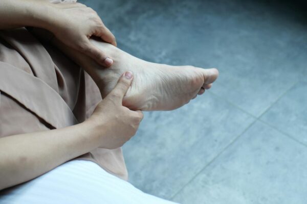 A woman massages her foot indoors, offering care and relaxation.